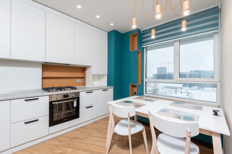 Cabinet with gas stove and oven against placemats on table under lights in modern apartment