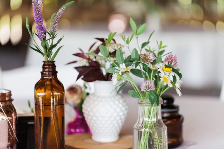 Charming floral arrangement in glass and brown bottles with daisies and wildflowers, perfect for rustic decor.