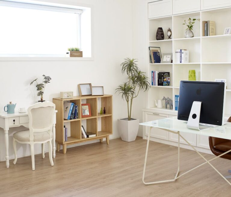 Contemporary home office setup with natural light, featuring modern decor, desk, computer, and bookshelves.