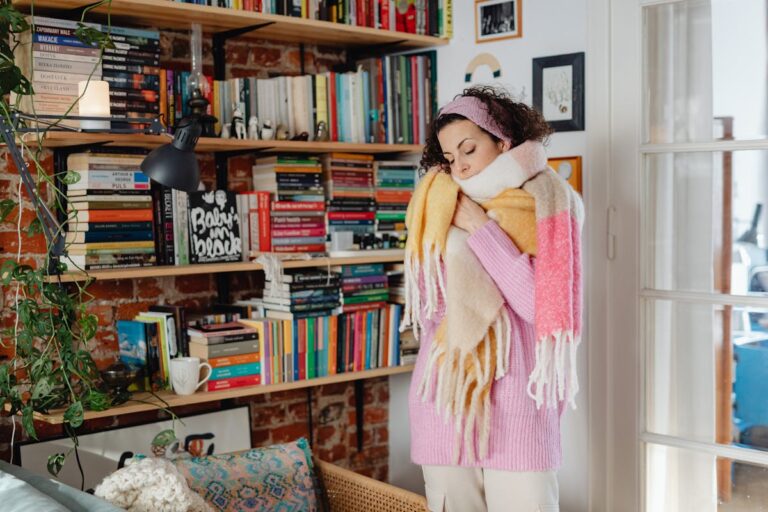A woman wrapped in scarves enjoys a quiet moment in her cozy home library.