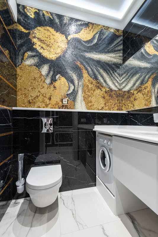 Elegant modern bathroom featuring mosaic art and integrated laundry machine.