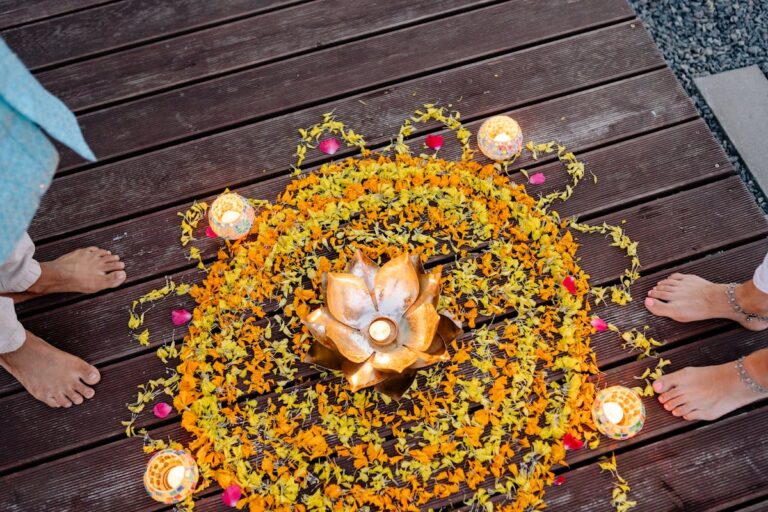 Overhead view of a vibrant floral Rangoli and candles, showcasing a traditional Diwali celebration.